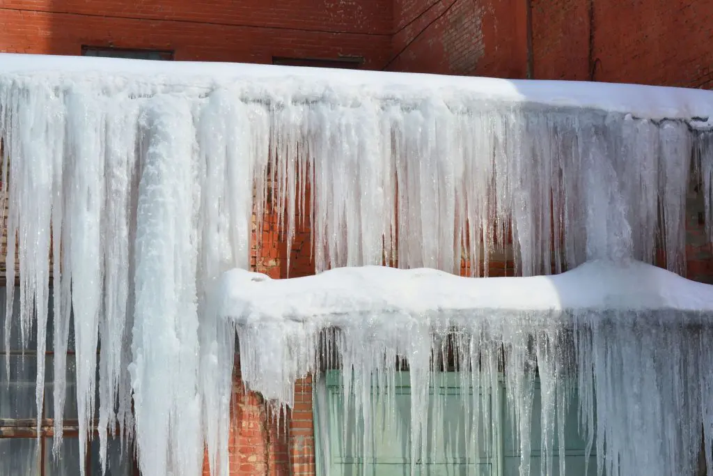 A home with severe ice dams and gigantic icicles hanging from the roof.